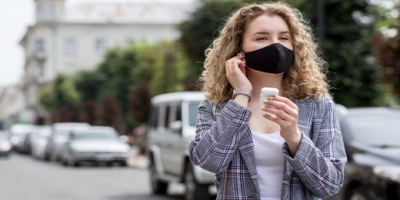 ragazza in città che si protegge naso, bocca e orecchie
